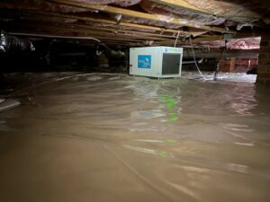 A crawl space with a dehumidifier and vapor barrier installed for moisture control by Eco Advantage Termite and Pest Solutions in Fayetteville, NC