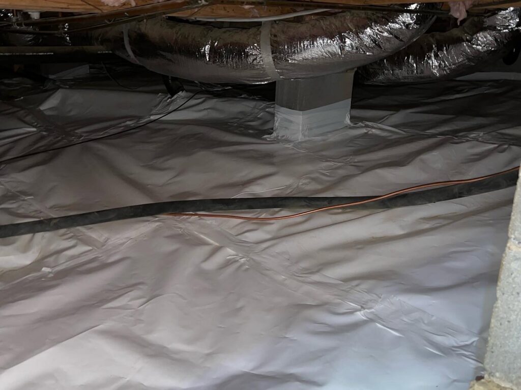 A crawl space with a white vapor barrier installed for moisture control by Venum Pest Solutions in Fayetteville, NC.