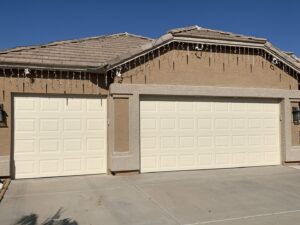 Two cream-colored residential garage doors on a house, installed by Fix It Now Garage Doors.com in Tempe, AZ.
