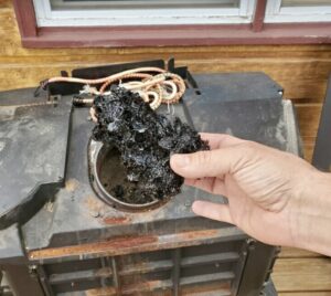 A hand holding a large piece of creosote removed during a chimney cleaning by Midtown Chimney Sweeps in Golden, CO.