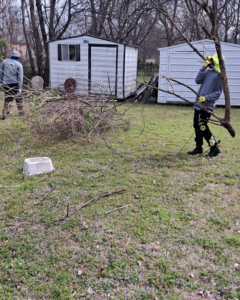 A lawn care crew clearing branches during a yard cleanup service by R & W Lawn care service LLC in Tulsa, OK.