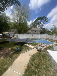 A crew installing white vinyl and black metal fences in a residential backyard by Fence Pros LLC in Medford, OR.