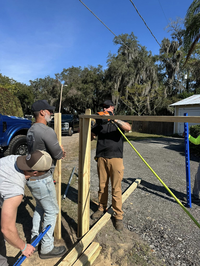 A crew of workers installing wooden fence posts for a new fence project by North East Fence and Forestry in North Bay, ON.