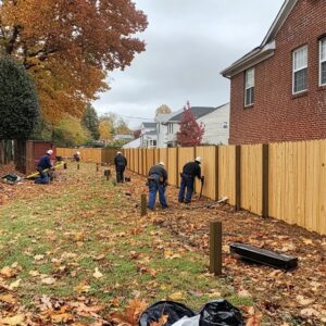 A crew of workers installing a new wooden privacy fence in a residential backyard for Roanoke Fence Company in Roanoke, VA.