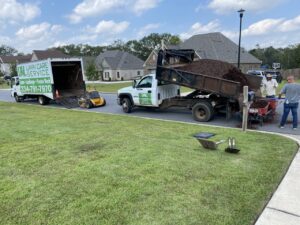 A crew unloading mulch from a dump truck for a landscaping project by L&L Lawn Care Service in Dothan, AL.