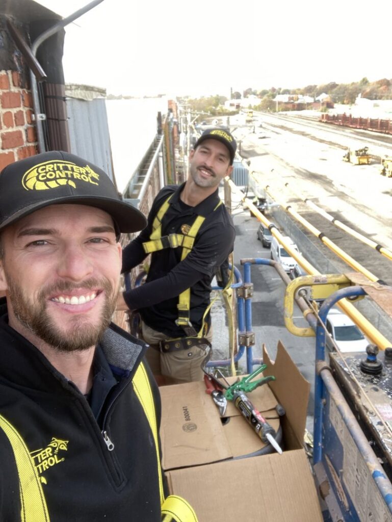 Critter Control technicians on a lift performing sealing work on a commercial building in Springfield, MO