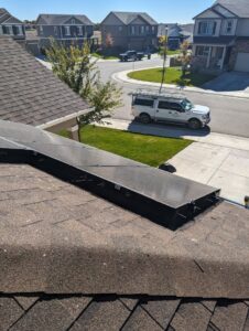 Critter guards installed under solar panels on a residential roof, with the Elevated Pest Control LLC truck in the driveway in Berthoud, CO.