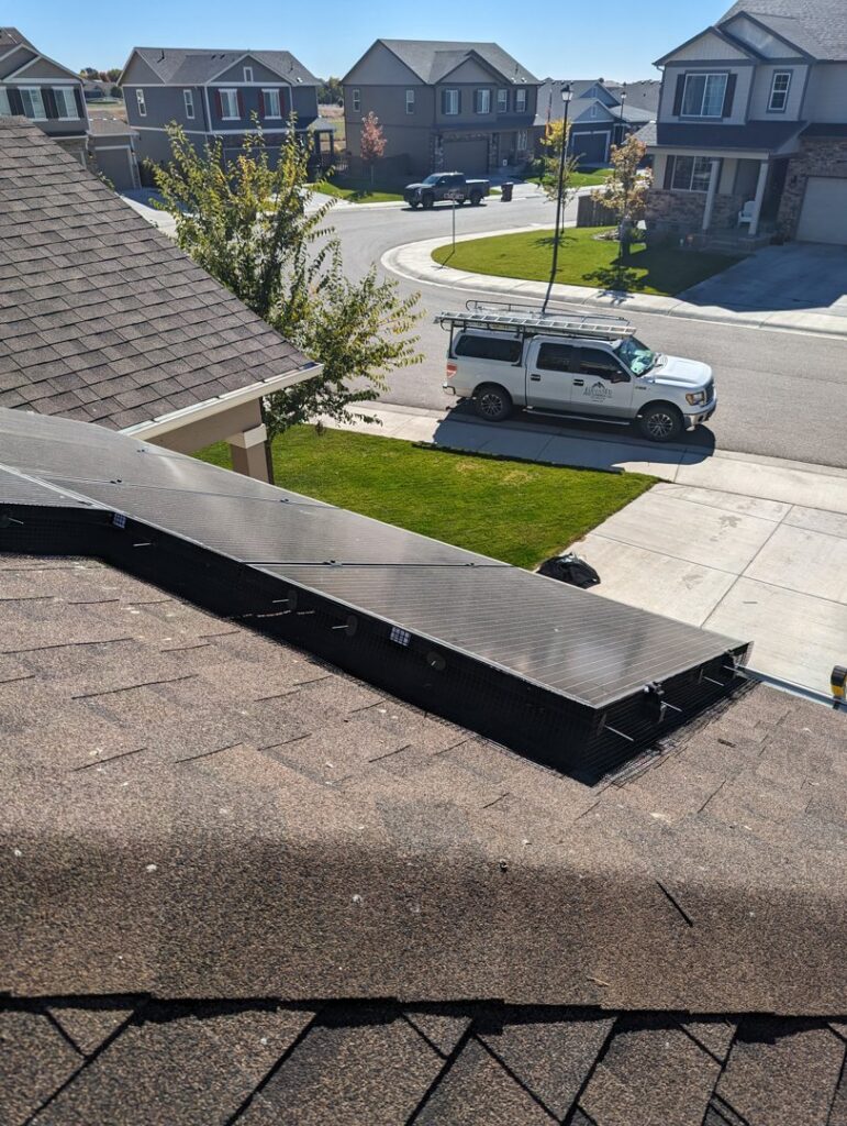 Critter guards installed under solar panels on a residential roof, with the Elevated Pest Control LLC truck in the driveway in Berthoud, CO.
