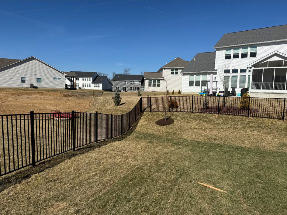 A curved section of a newly installed black aluminum fence in a backyard by BK FenceWorks in Wentzville, MO.