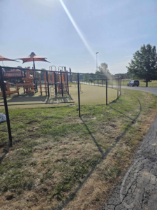 A curved section of black chain-link fence surrounding a playground area, installed by Atchison Fence in Effingham, KS.
