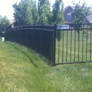 A curved black metal fence installed in a residential area by Mann Fence Co., Inc. in Olathe, KS.