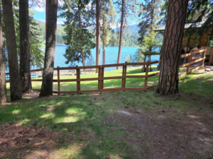 A curved wooden fence with wire mesh installed along a beautiful lakeside property by EcoGreen Fencing in Coeur d'Alene, ID.