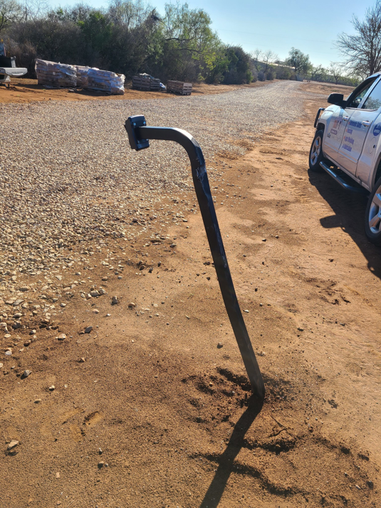 A curved metal fence post newly installed in the ground by S.A. SAF-T Systems, LLC in San Antonio, TX.