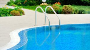 A curved pool with blue tile coping and handrails by Midwest Custom Pools, LLC in Lawrence, KS.
