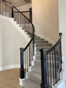Elegant curved staircase with new gray carpet and black railings, installed by Castro's Carpet in Houston, TX.