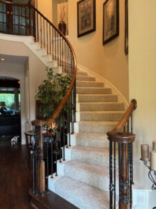 Elegant curved staircase with new carpet installation by Peek's Floor Co., a carpet contractor in Dallas, TX.