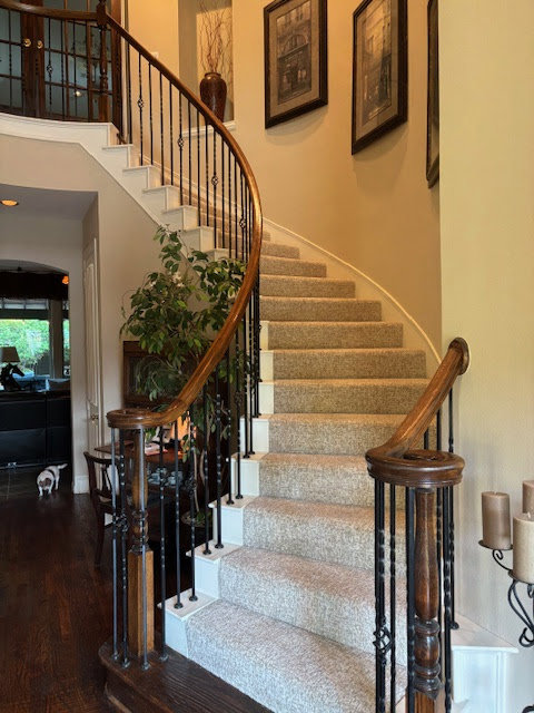 Elegant curved staircase with new carpet installation by Peek's Floor Co., a carpet contractor in Dallas, TX.