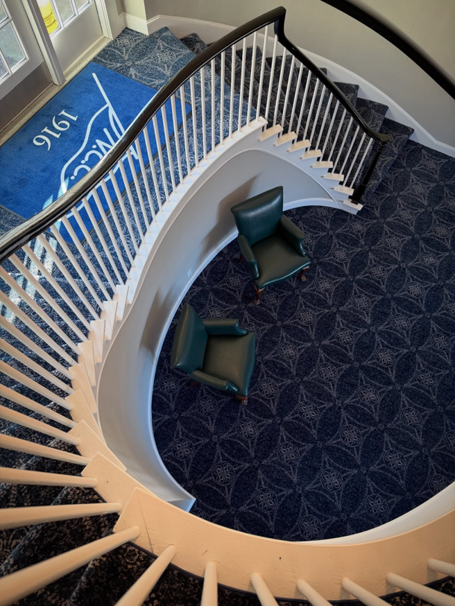 Elegant blue patterned wall-to-wall carpet installed on a curved staircase and landing by Persian Rug Gallery in Nashua, NH.