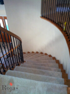 A beautifully carpeted curved staircase with light-colored carpet, showcasing expert installation by Rojas Carpet and Flooring in Denver, CO.