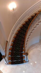 A luxurious patterned carpet runner installed on a curved staircase by Carpet Art of America in O'Fallon, MO.