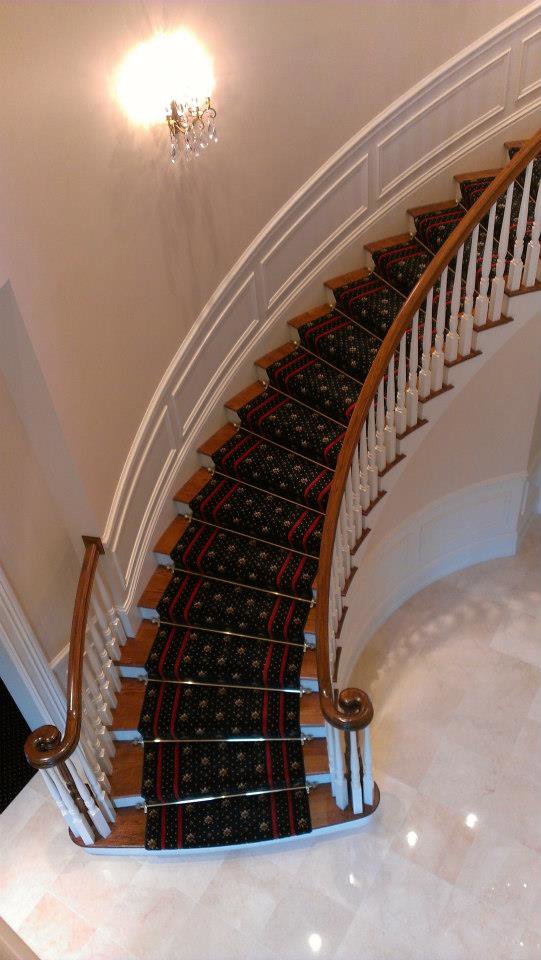 A luxurious patterned carpet runner installed on a curved staircase by Carpet Art of America in O'Fallon, MO.