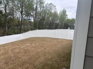 A curved white vinyl privacy fence enclosing a residential backyard by Superior Fence & Rail of Charlotte, NC