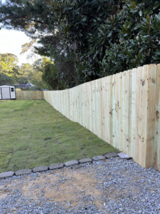 A curved wood privacy fence installed along a property line with a new lawn by First in Fencing and Remodeling in Fayetteville, NC.
