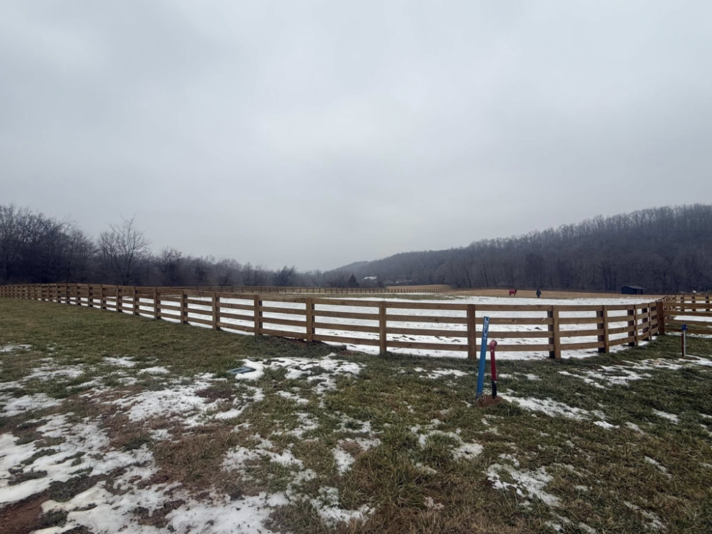 A curved section of newly installed wooden ranch fence in a snowy field by Richards Fencing in Lynnville, TN