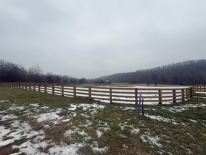 A curved section of newly installed wooden ranch fence in a snowy field by Richards Fencing in Lynnville, TN