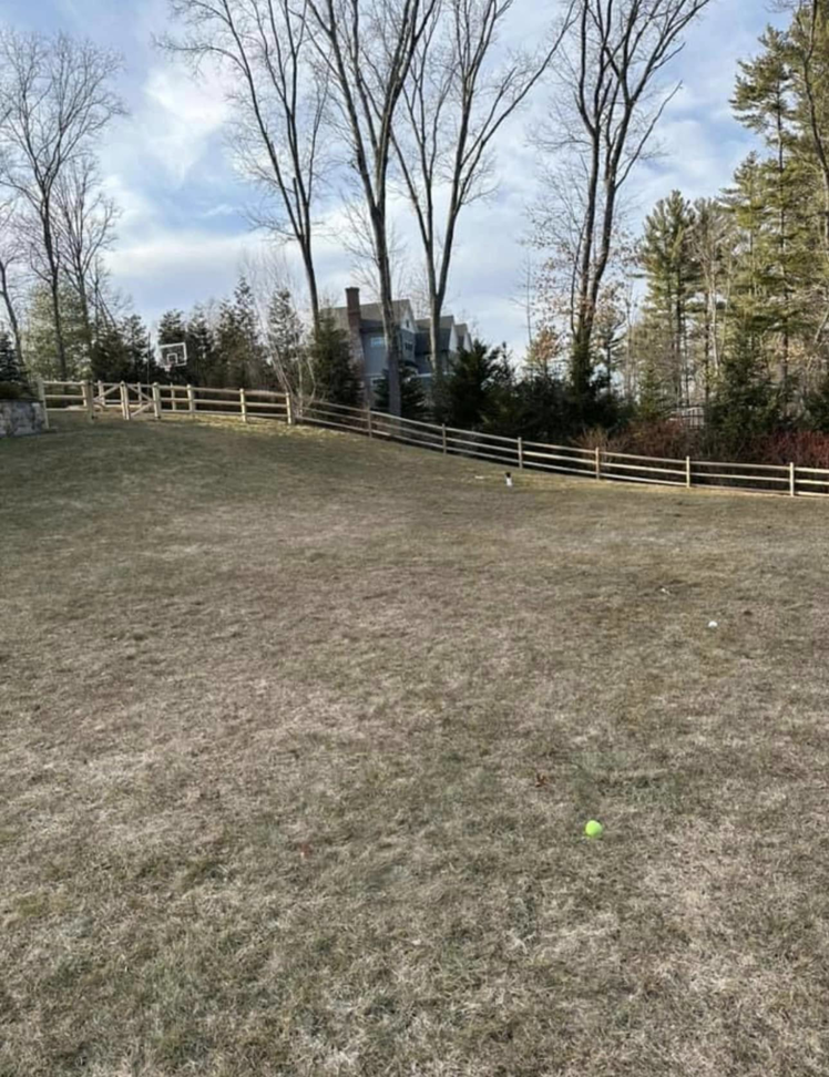 A curved wooden split-rail fence installed on an incline by Hunter & Sons Fence in Burlington, MA.