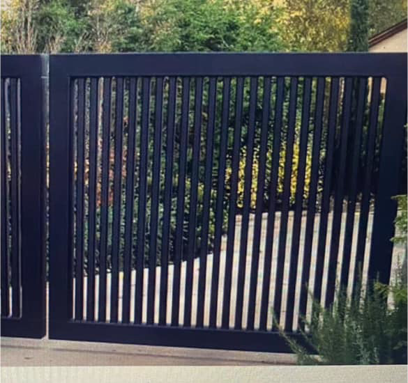 A custom-designed black metal driveway gate with vertical slats, installed by Gonzalez Iron Work in Oakland, CA.