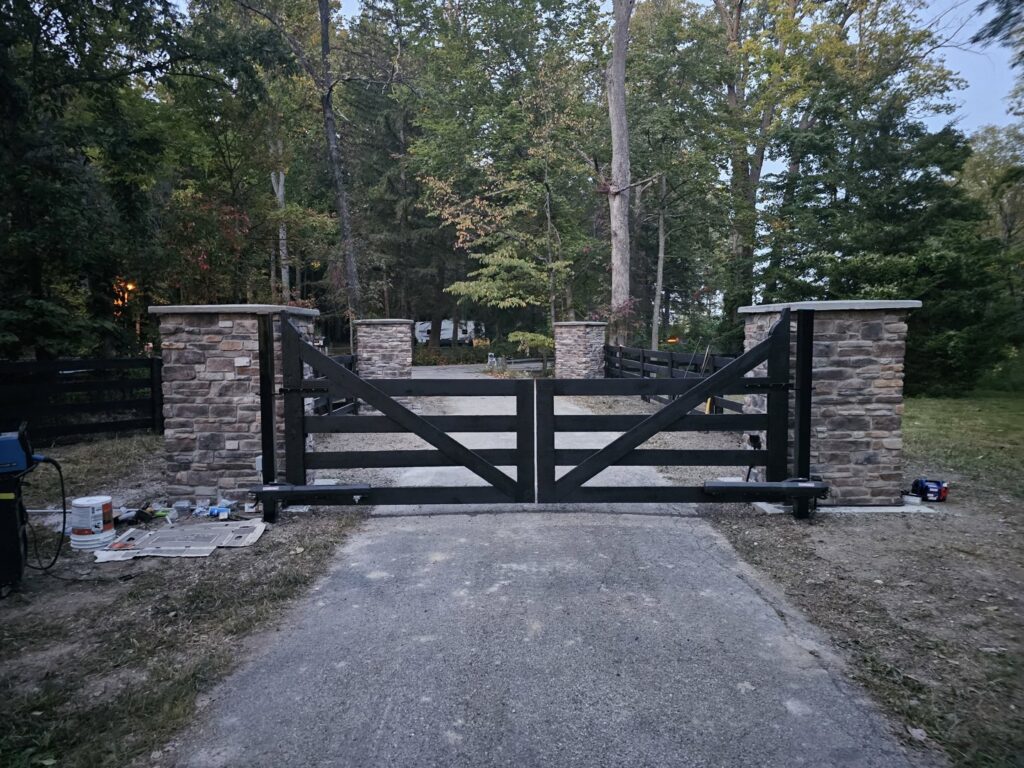 A custom black wooden gate with stone pillars installed at a property entrance by Affordable Fence Builders in Dayton, OH.