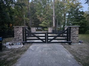 A custom black wooden gate with stone pillars installed at a property entrance by Affordable Fence Builders in Dayton, OH.