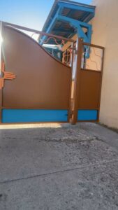 A custom brown and blue metal gate with a New Mexico Zia symbol, installed by City Iron LLC in Albuquerque, NM.