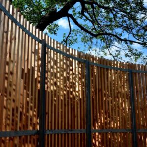 A custom-built curved wood slat fence with metal posts, installed by Midwest Legacy Fence & Deck in Aurora, IL.