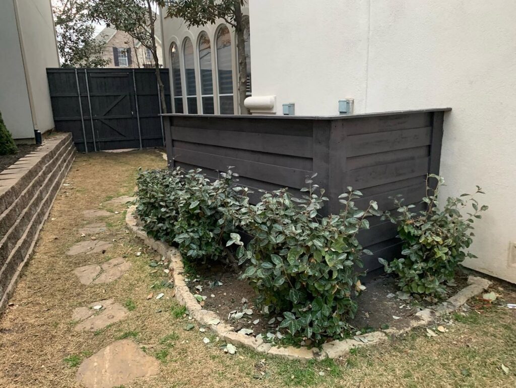 A custom dark wood privacy screen and gate installed next to a home by G L Fence & Remodeling in Arlington, TX.