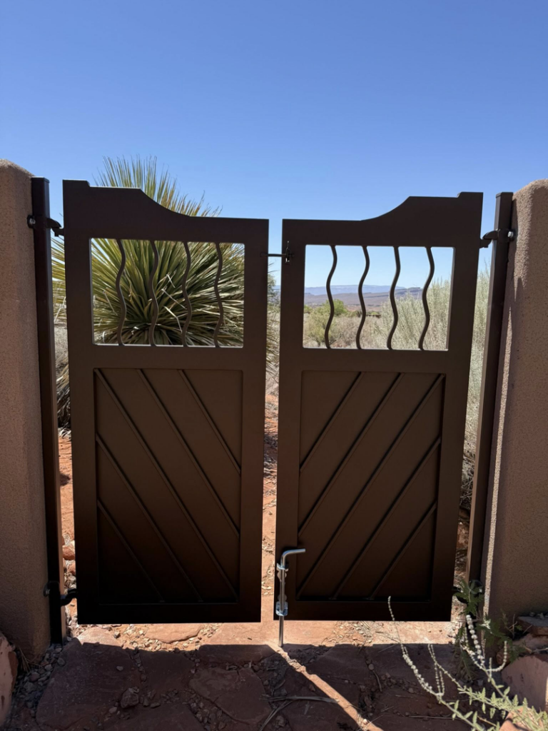 A newly installed custom decorative metal gate by Legacy Fencing LLC, enhancing a stucco wall in St. George, UT.