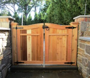 A custom double wooden gate with decorative stone pillars installed by Integrous in Gap, PA