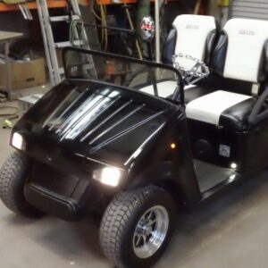 A black custom golf cart with bright headlights, serviced by Advanced Golf & Electric Vehicles in Orlando, FL.