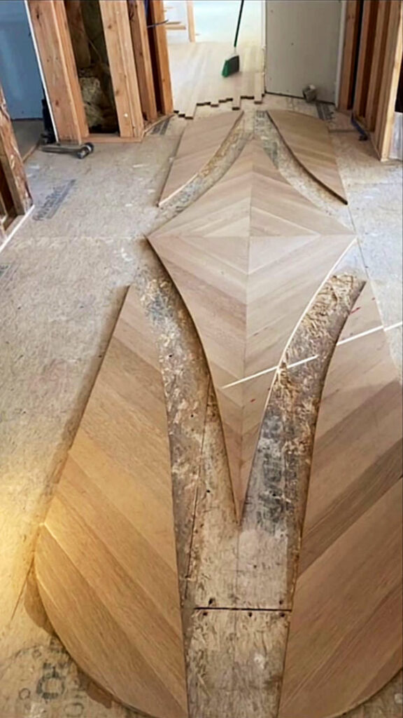 An intricate custom hardwood floor design being laid out during installation by Isad Home Floor in Bridgeport, CT.
