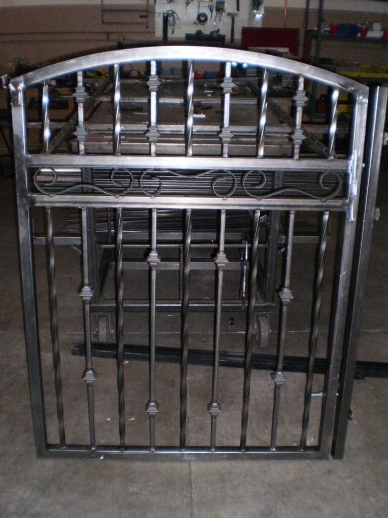 A custom-fabricated metal gate with an arched top in a workshop, created by Done Wright Fencing and Welding in Denver, CO.