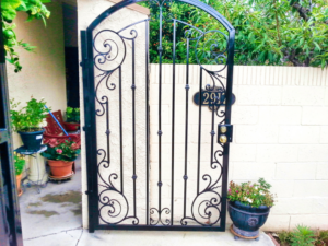 A custom ornate black iron pedestrian gate with a house number and doorbell installed by HBHB Iron Works in Los Angeles, CA.