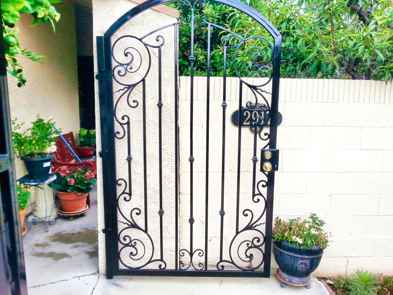 A custom ornate black iron pedestrian gate with a house number and doorbell installed by HBHB Iron Works in Los Angeles, CA.