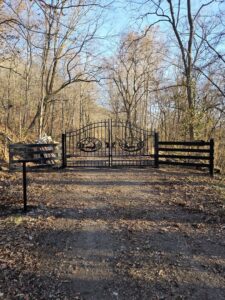 Custom ornate metal gate with animal designs installed in a wooded setting by National Fence and Gate in Ironton, MO.