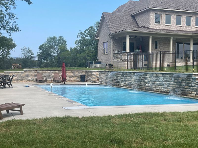 A custom pool featuring decorative stone waterfalls, a project by Luxury Outdoors, your pool contractor in Murfreesboro, TN.