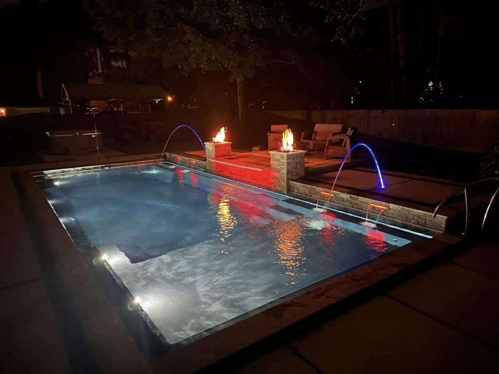 A custom-designed swimming pool with illuminated water features and fire pits by Central Pools, Inc. in Baton Rouge, LA.