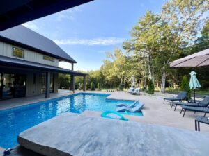 A custom-shaped inground pool with spacious concrete patio and lounge chairs, designed by Riverstone LLC in Bowling Green, KY.