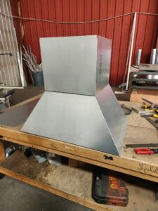Custom sheet metal ductwork or a ventilation hood fabricated on a workbench by High Standard HVAC LLC in Cheyenne, WY.