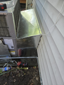 Custom sheet metal ductwork being installed next to an outdoor AC unit by Jesse's HVAC LLC in Newport News, VA.