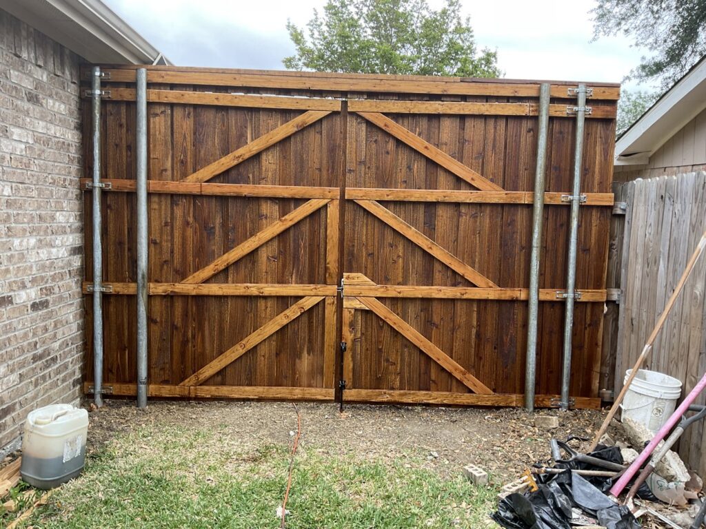 A custom-stained double wood gate with sturdy metal posts, expertly installed by G L Fence & Remodeling in Arlington, TX.